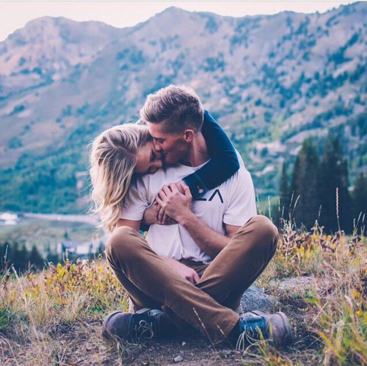 Мужчина имеет молодую. Счастливые отношения. Красивые влюбленные пары. Поцелуй в горах. Объятия на природе.